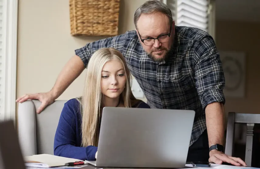 Father and daughter, looking at a laptop, discovering what happens after they file the FAFSA.