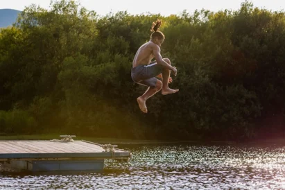 Must do items for college students in the summer. A boy jumping into the lake.