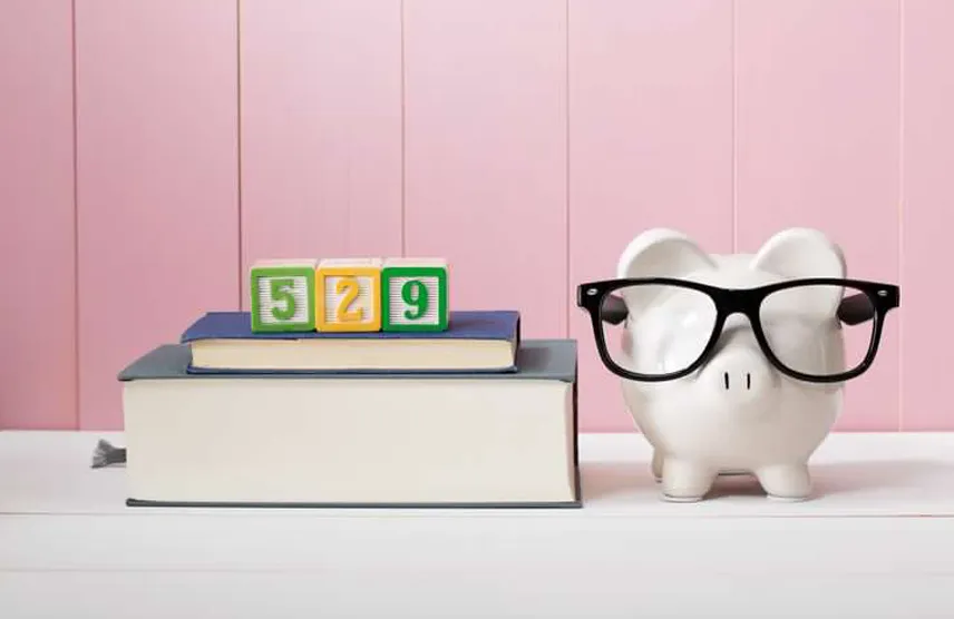 September is College Savings Month - Consider a 529 Plan! Piggy bank next to a stack of books with 529 in blocks.